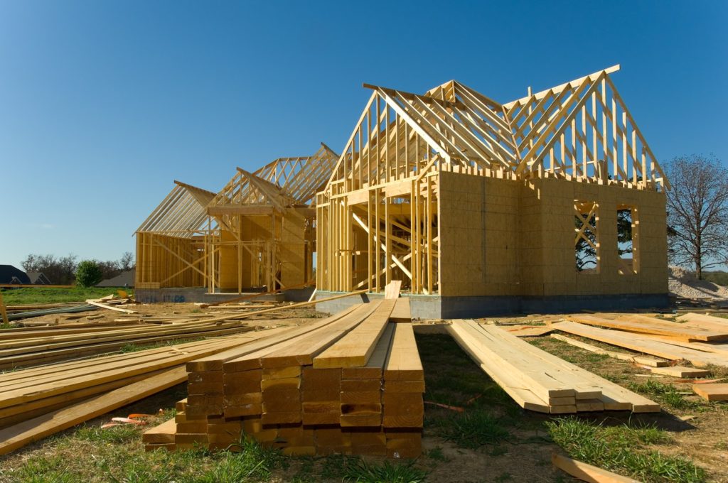 New home under construction with wood, trusses and supplies against blue sky