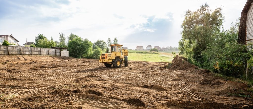 large yellow wheel loader aligns a piece of land for a new building