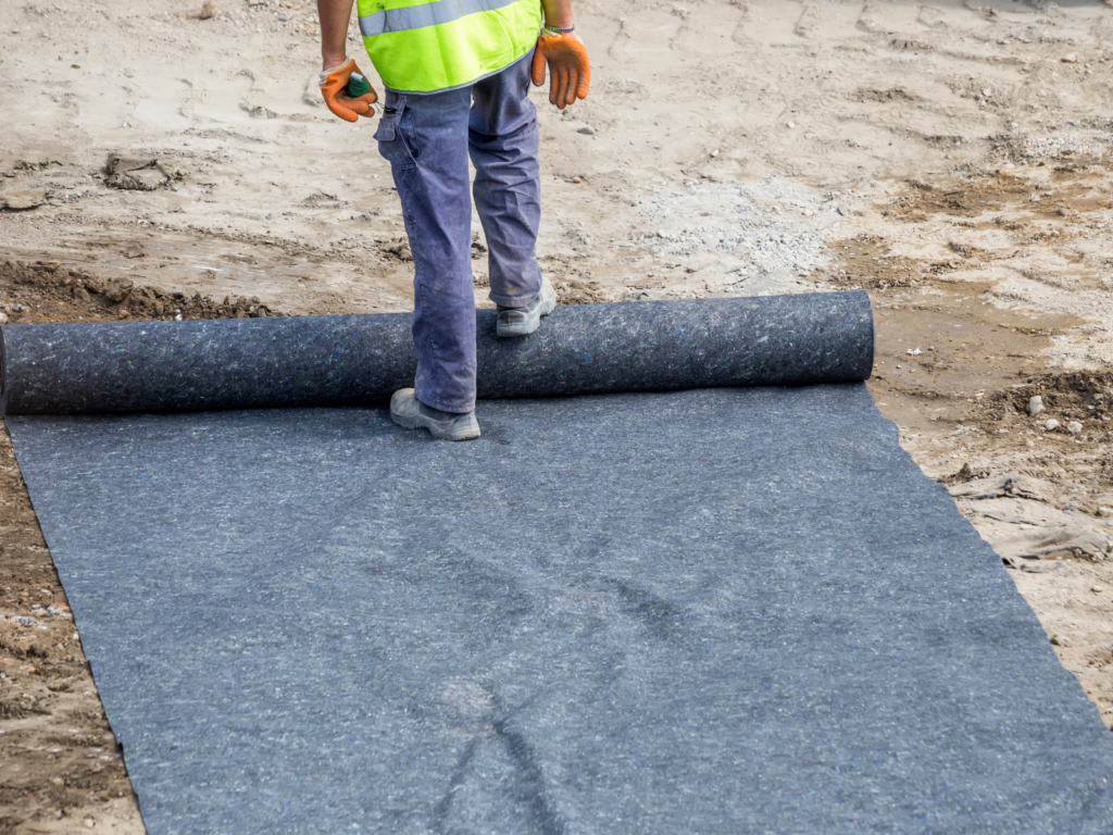 Geotextile Fabric Big Construction worker laying out a Geotextile Fabric
