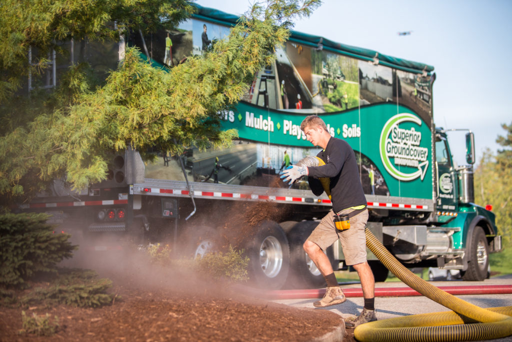 Superior Groundcover team member installing playground mulch in front of one of our trucks
