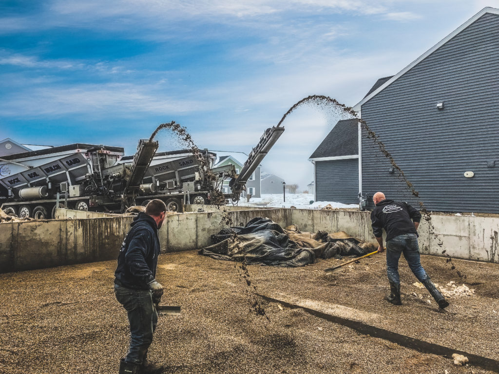 professionals working on a crushed stone installation project with a stone slinger truck