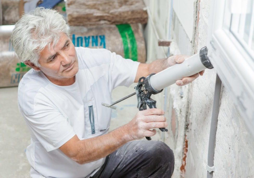 Handyman caulking a window frame